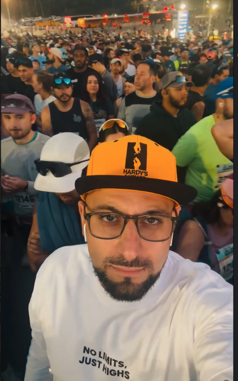 Chris Hardy in a Hardy's cap at a marathon start line among runners